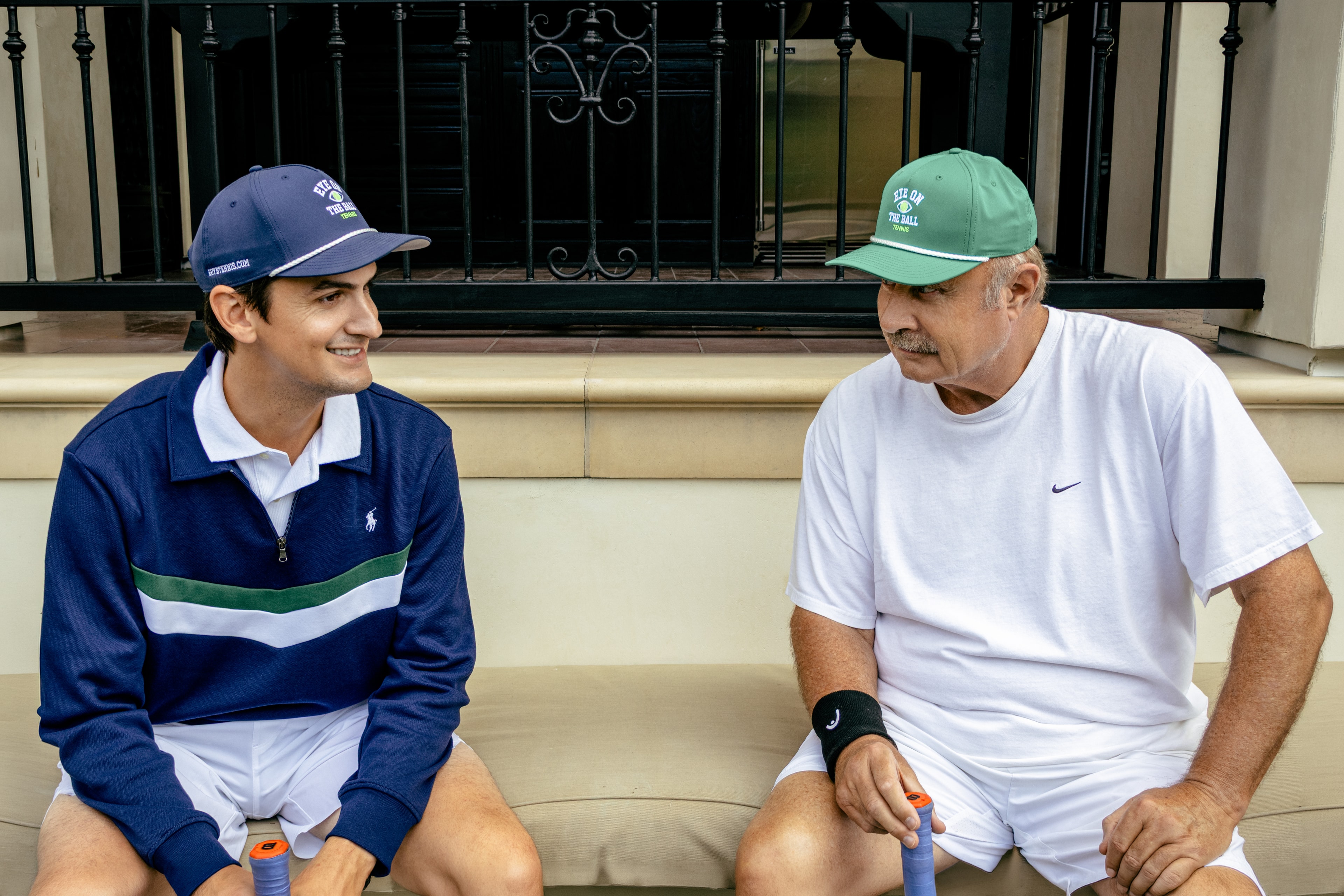 Mark Douglas Foti and Dr. Phil McGraw sitting together in Eye on the Ball tennis hats.