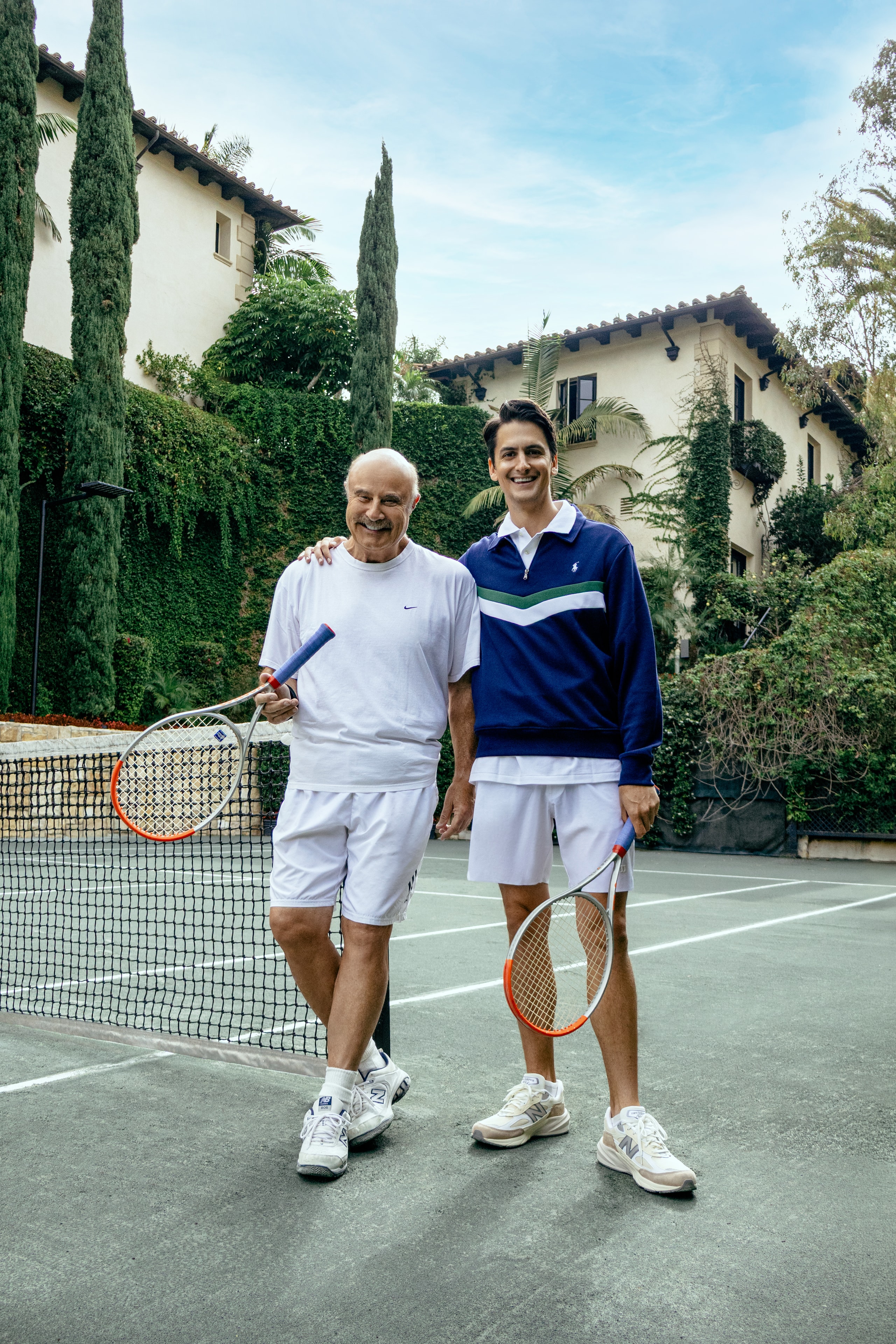 Mark Douglas Foti and Dr. Phil McGraw smiling together beside the tennis net.
